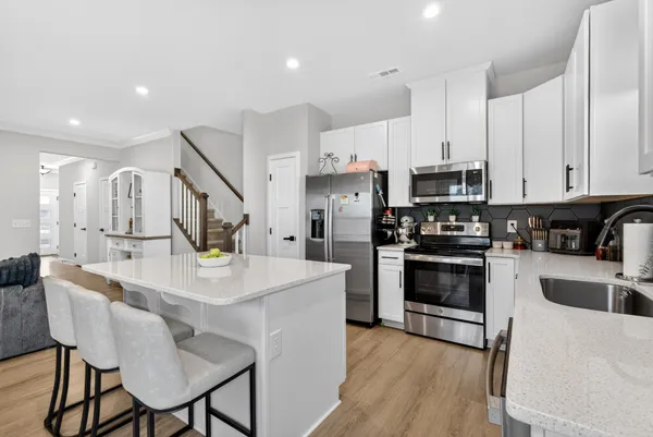 a kitchen with stainless steel appliances kitchen island granite countertop a refrigerator a stove a sink a dining table and chairs with wooden floor
