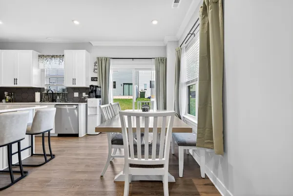 a kitchen with stainless steel appliances kitchen island granite countertop a refrigerator a stove a microwave oven a dining table and chairs with wooden floor
