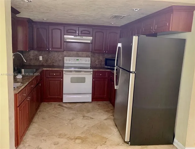 a kitchen with stainless steel appliances granite countertop a refrigerator stove a sink and a oven