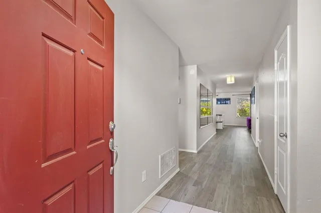 a view of a hallway with wooden floor windows and a bathroom