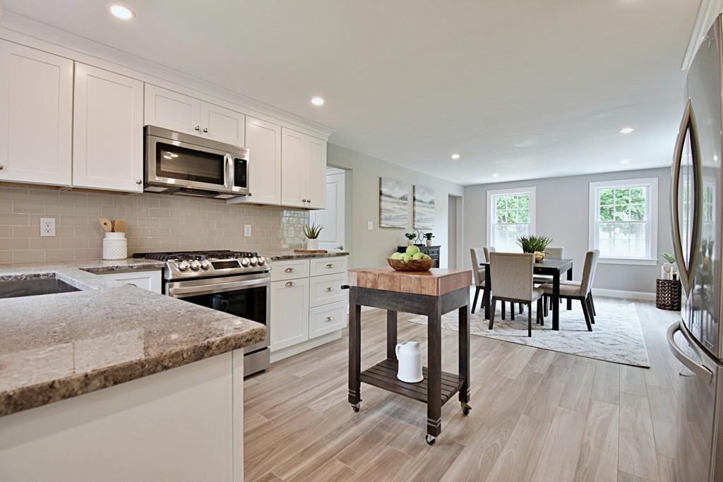 65 Spaulding Road Chelmsford, MA 01824 - Photo 6 of 42 a kitchen with stainless steel appliances granite countertop a stove top oven a sink a dining table and chairs with wooden floor