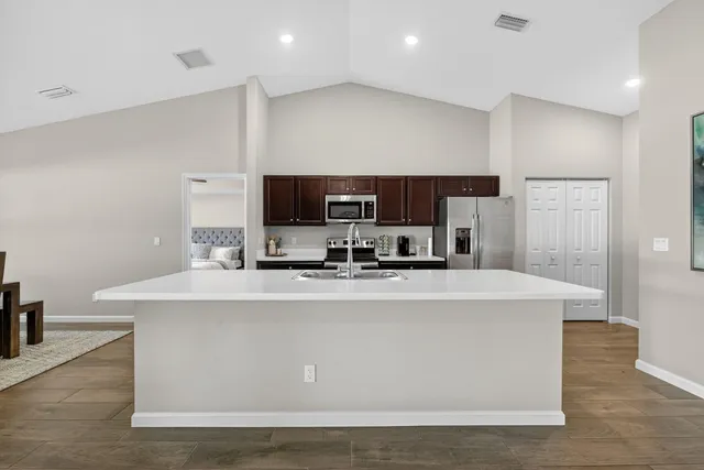 a view of kitchen with stainless steel appliances a stove top oven a sink with island and chairs