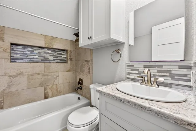 a bathroom with a granite countertop sink a toilet and bathtub