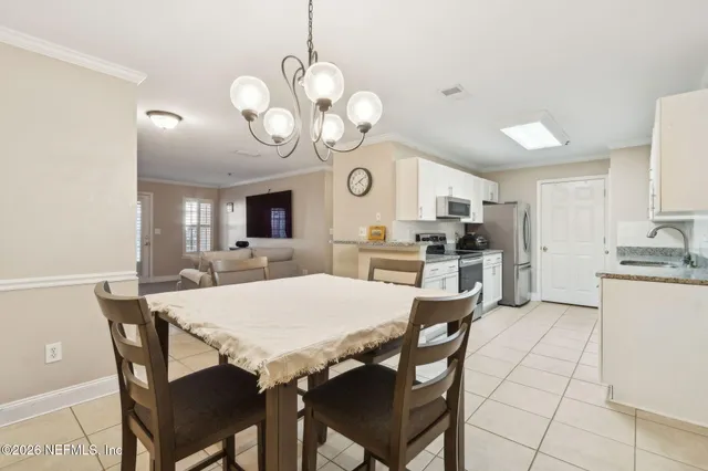 a view of a dining room and kitchen with furniture a chandelier and wooden floor