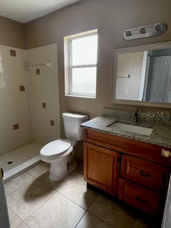 a bathroom with a granite countertop toilet sink and mirror