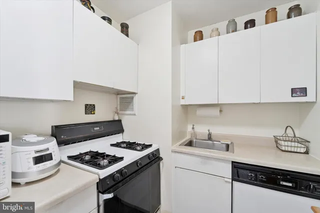 a kitchen with stainless steel appliances a white stove top oven and white cabinets