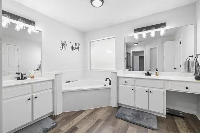 a spacious bathroom with a double vanity sink mirror and bathtub