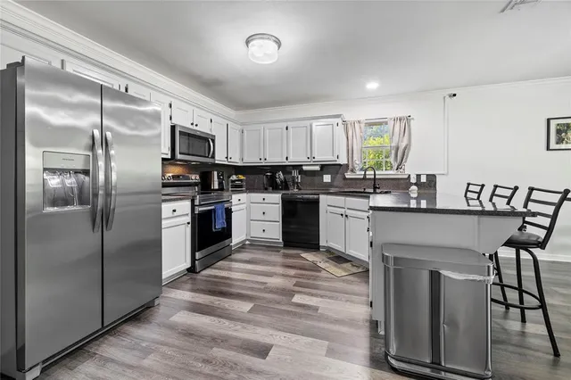 a kitchen with stainless steel appliances granite countertop a stove top oven a sink and a refrigerator