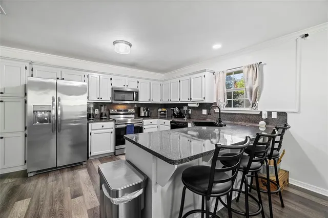a kitchen with stainless steel appliances granite countertop a stove a sink a refrigerator a dining table and chairs