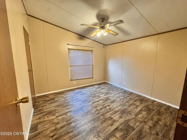 an empty room with wooden floor and fan