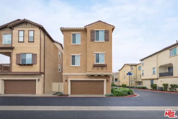 a view of an empty room with wooden floor and kitchen view