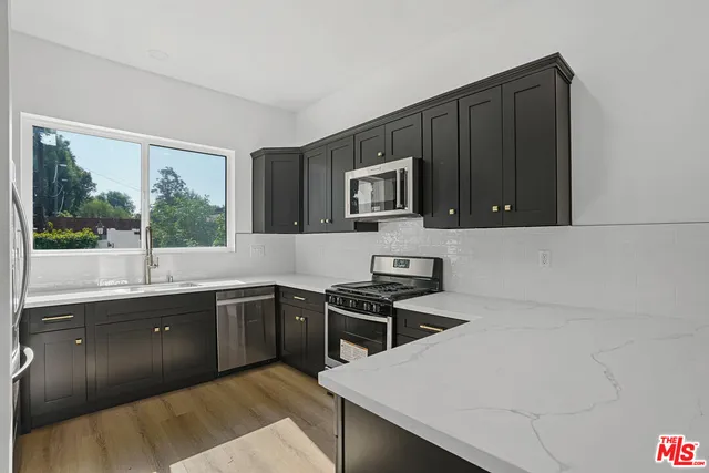 a kitchen with stainless steel appliances granite countertop a sink stove and microwave
