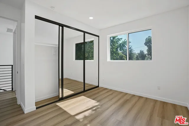 a view of an empty room with window wooden floor