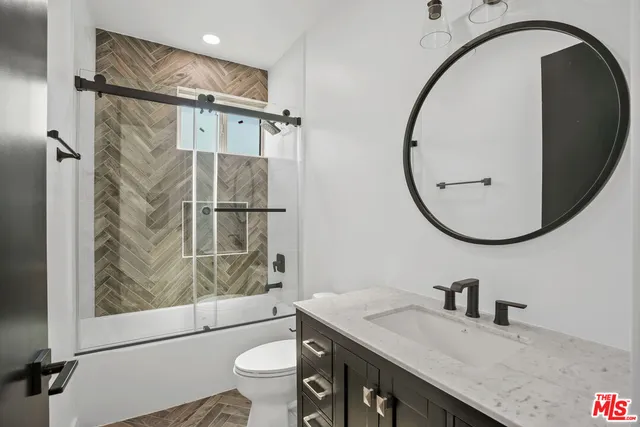 a bathroom with a granite countertop sink mirror vanity and toilet