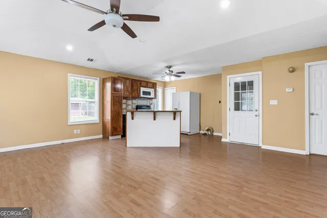 a view of a kitchen with a refrigerator a ceiling fan and wooden floor