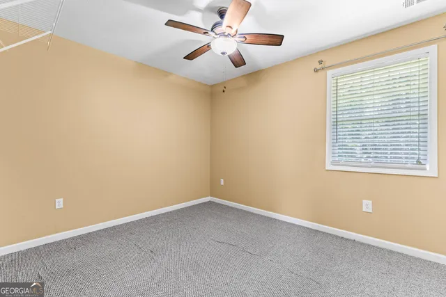 an empty room with a window and a fan