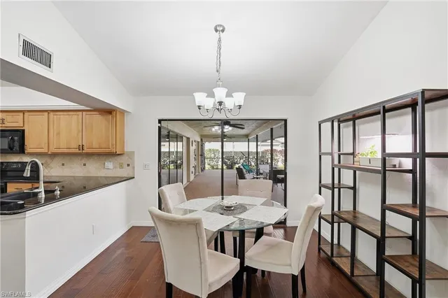 a kitchen with stainless steel appliances kitchen island granite countertop a stove a sink a dining table and chairs with wooden floor