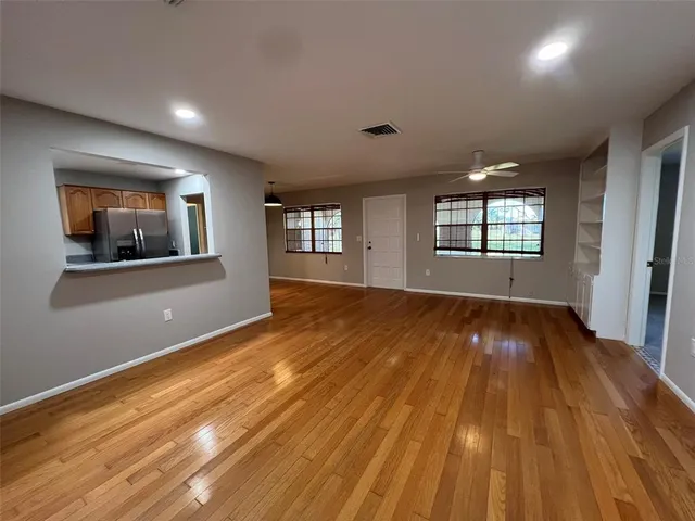 a view of an empty room with a window and wooden floor