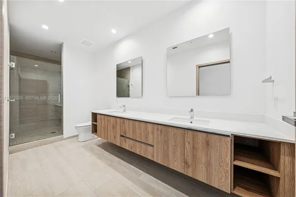 a bathroom with a double vanity sink mirror and shower