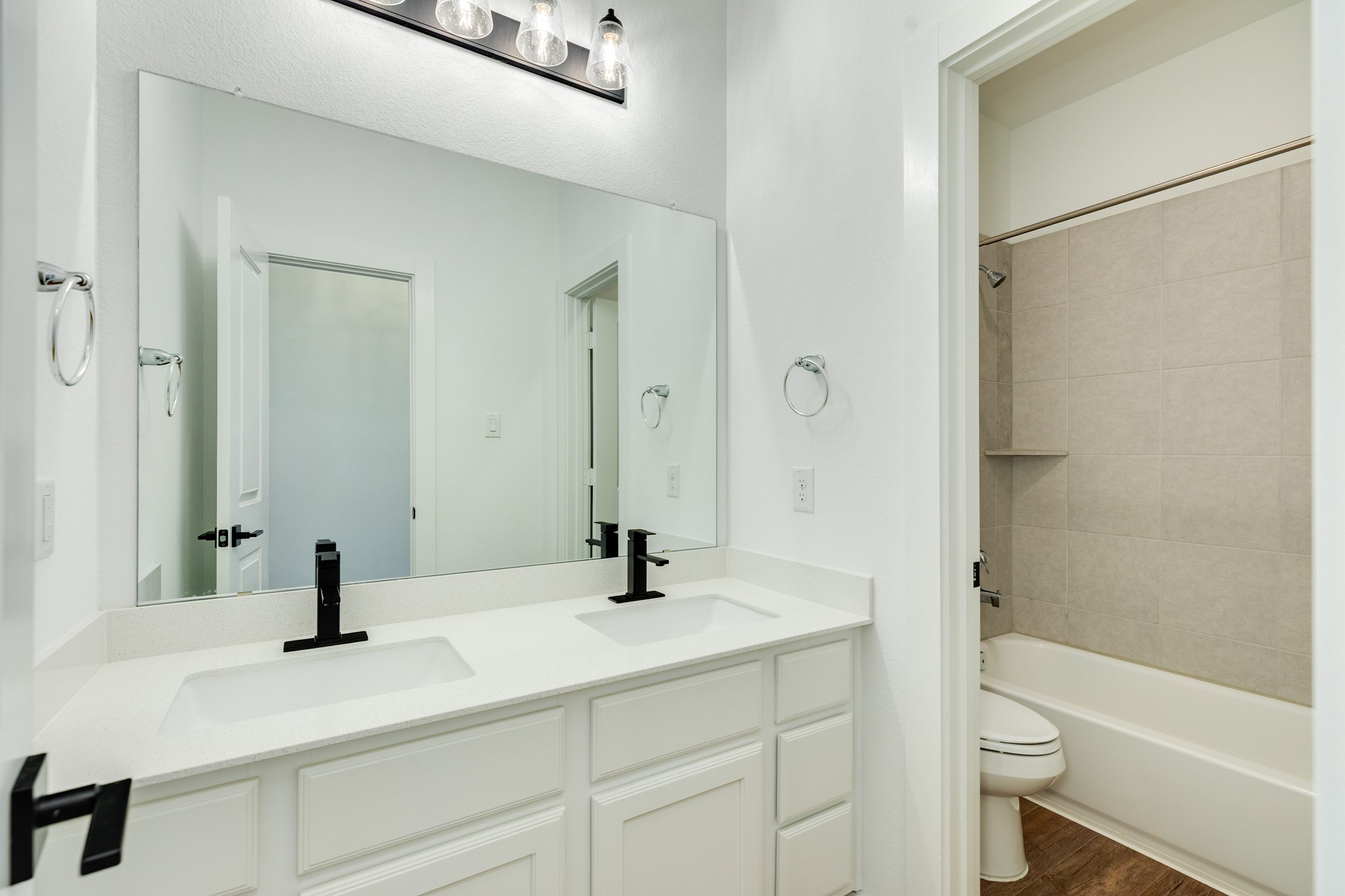 3806 Shackleton Court Rosharon, TX 77583 - Photo 9 of 50 This full bath is shared by both secondary bedrooms. It features quartz countertops, appealing black hardware, a large mirror, double sinks, and a private tub area.