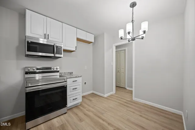 a kitchen with stainless steel appliances granite countertop a sink dishwasher a stove and a microwave oven with cabinets