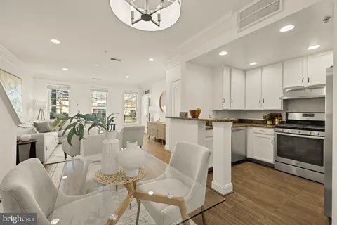 a kitchen with stainless steel appliances granite countertop a stove top oven a refrigerator a sink and white cabinets with wooden floor