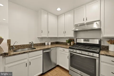 a kitchen with granite countertop white cabinets and stainless steel appliances