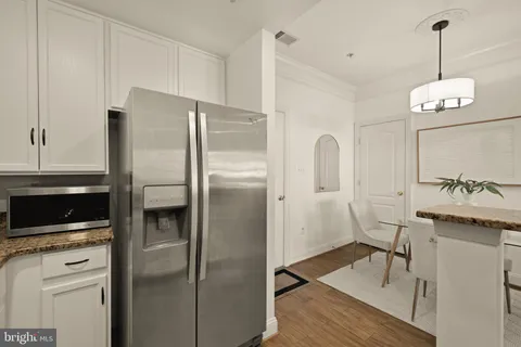 a kitchen with stainless steel appliances granite countertop a refrigerator a stove and a sink with wooden floor