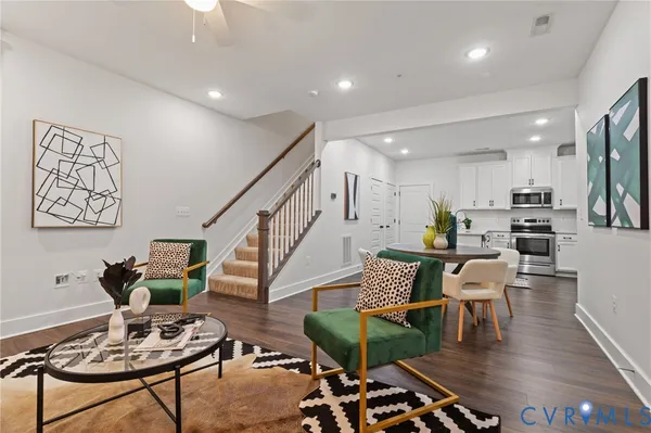 a living room with furniture kitchen view and a wooden floor