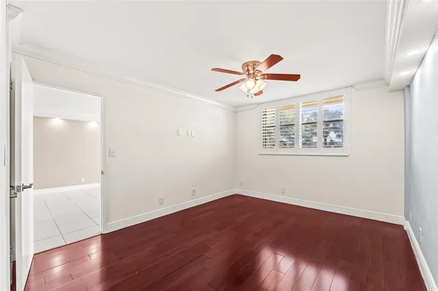 an empty room with wooden floor and a ceiling fan