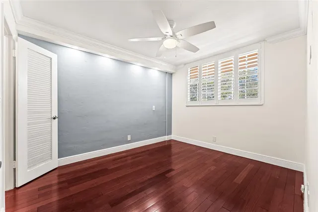 an empty room with wooden floor and fan