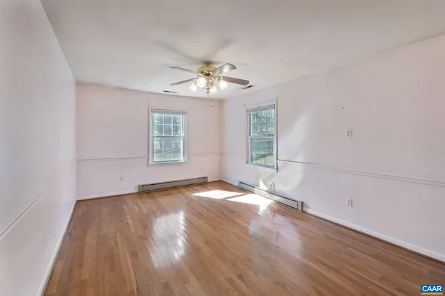 a view of empty room with wooden floor and fan