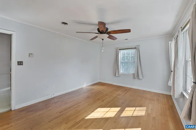 a view of empty room with wooden floor and fan