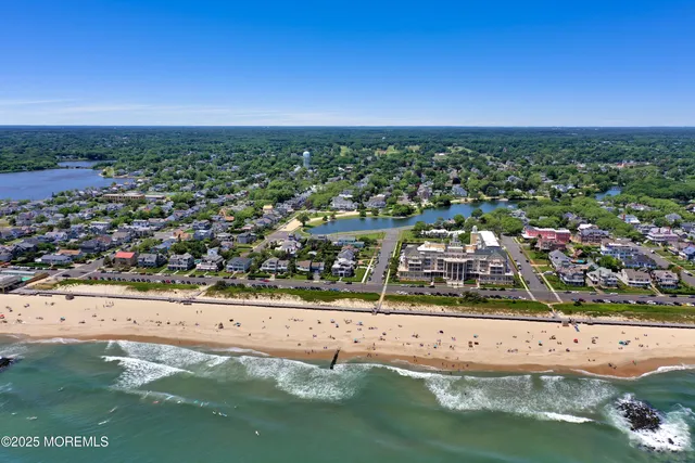 an aerial view of ocean and residential houses with outdoor space