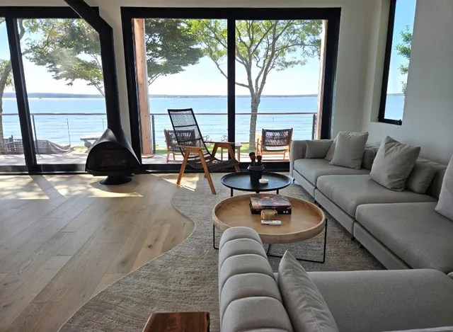 a view of a patio with table and chairs under an umbrella with large trees