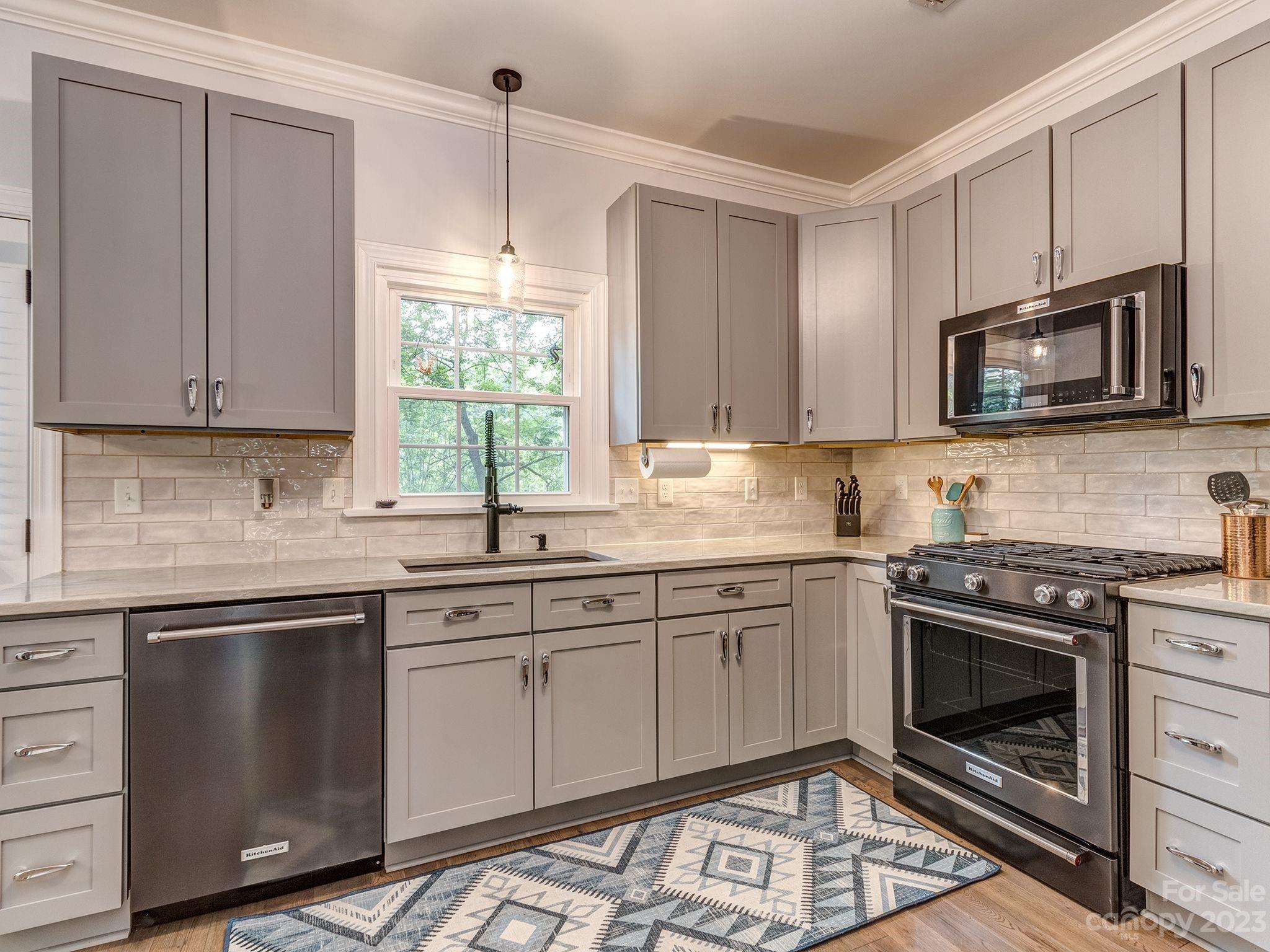 a kitchen with granite countertop a stove sink and microwave