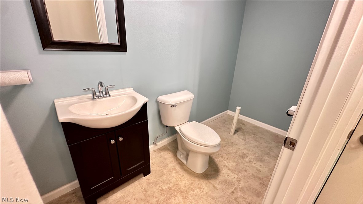 2603 Rockefeller Road Wickliffe, OH 44092 - Photo 29 of 34 Powder room featuring a dark wood-finish vanity with an integrated white basin, a mirror with a dark wood-finish frame, and light-toned flooring