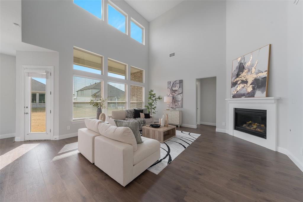 4028 Yellow Jasmine Lane Heath, TX 75126 - Photo 4 of 38 Living area with dark wood-style flooring, a glass covered fireplace, visible vents, and baseboards