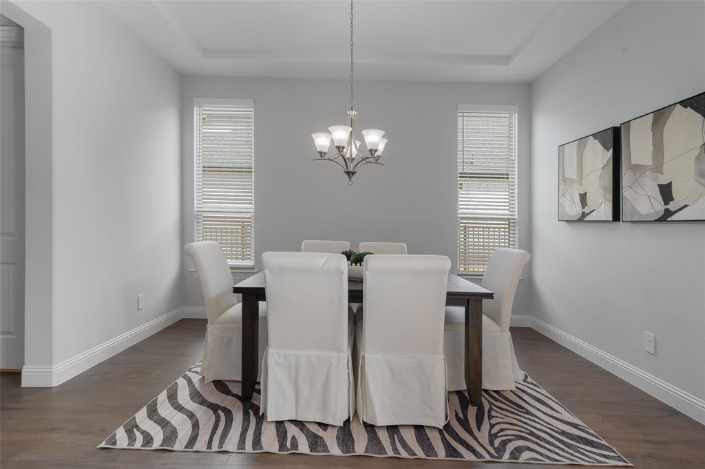 4028 Yellow Jasmine Lane Heath, TX 75126 - Photo 6 of 38 Dining space featuring a chandelier, dark wood-type flooring, a raised ceiling, and baseboards