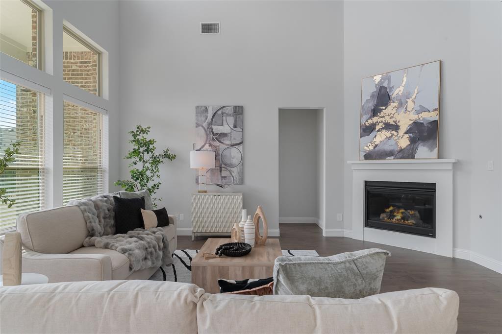 4028 Yellow Jasmine Lane Heath, TX 75126 - Photo 8 of 38 Living room with dark wood finished floors, visible vents, a towering ceiling, a glass covered fireplace, and baseboards