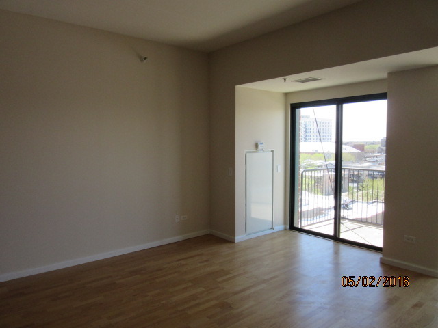 4848 North Sheridan Road, Unit 802 Chicago, IL 60640 - Photo 5 of 11 an empty room with wooden floor and windows with curtains