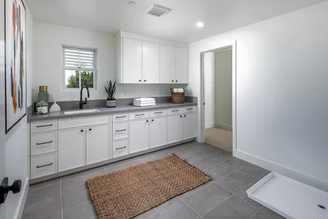 a kitchen with white cabinets and window