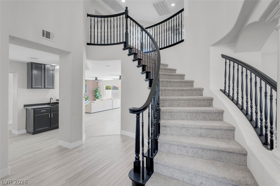 3604 North Campbell Road Las Vegas, NV 89129 - Photo 10 of 54 Staircase featuring wood finished floors, baseboards, and a high ceiling