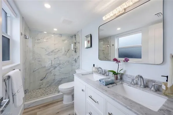 a bathroom with a granite countertop sink toilet a large mirror a shower and a mirror