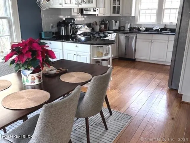 a kitchen with stainless steel appliances granite countertop a table chairs stove and white cabinets