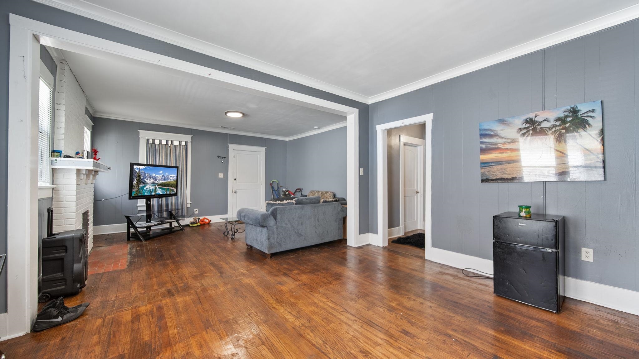 659 Decatur Street Memphis, TN 38107 - Photo 9 of 24 Spacious living area featuring wood-finish flooring, light gray walls, white trim, and a white brick fireplace