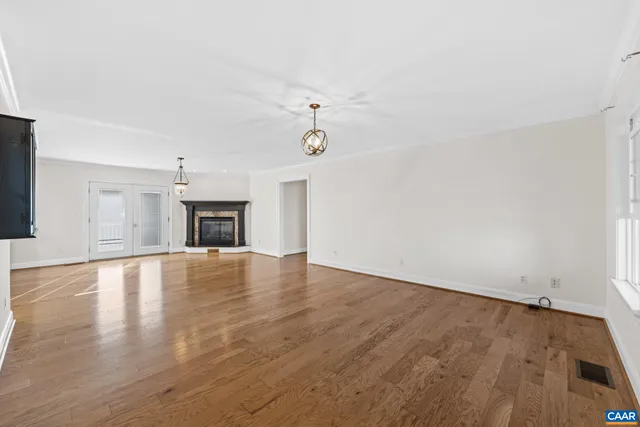 an empty room with wooden floor fireplace and a window