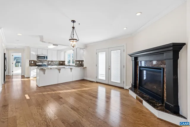 a living room with stainless steel appliances furniture a fireplace a flat screen tv and view kitchen