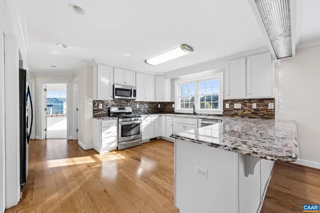 a kitchen with granite countertop a stove sink cabinets and window