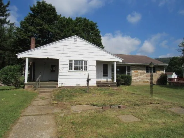 a front view of a house with a garden and trees